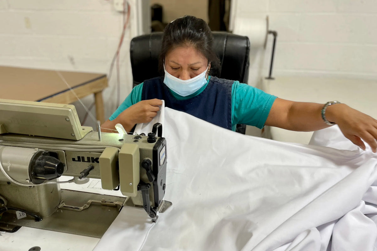 Person hand sewing Signature Sheets.