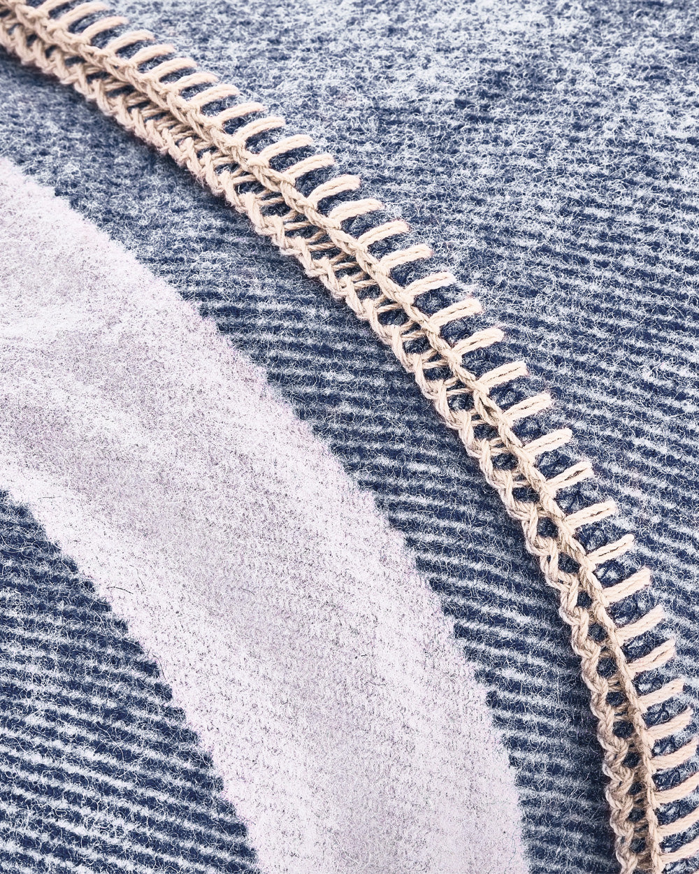 Detail shot of the Denim Blue Northwest Wool Throw, with emphasis on the weave, striped pattern, and whipstitched edge.