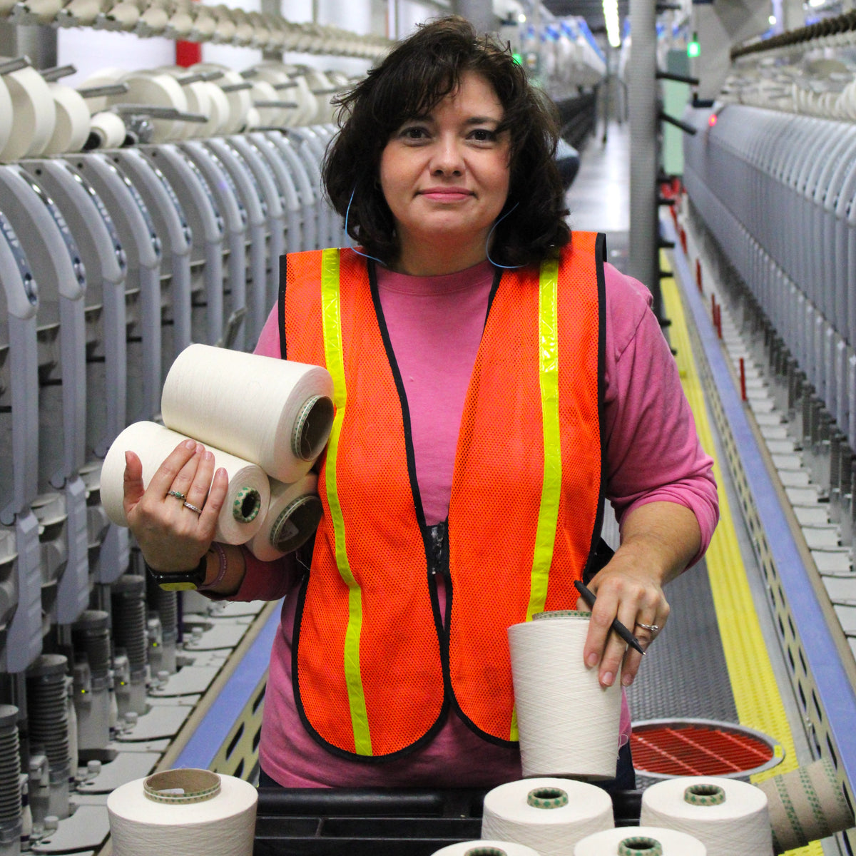 american worker holding cones of cotton yarn